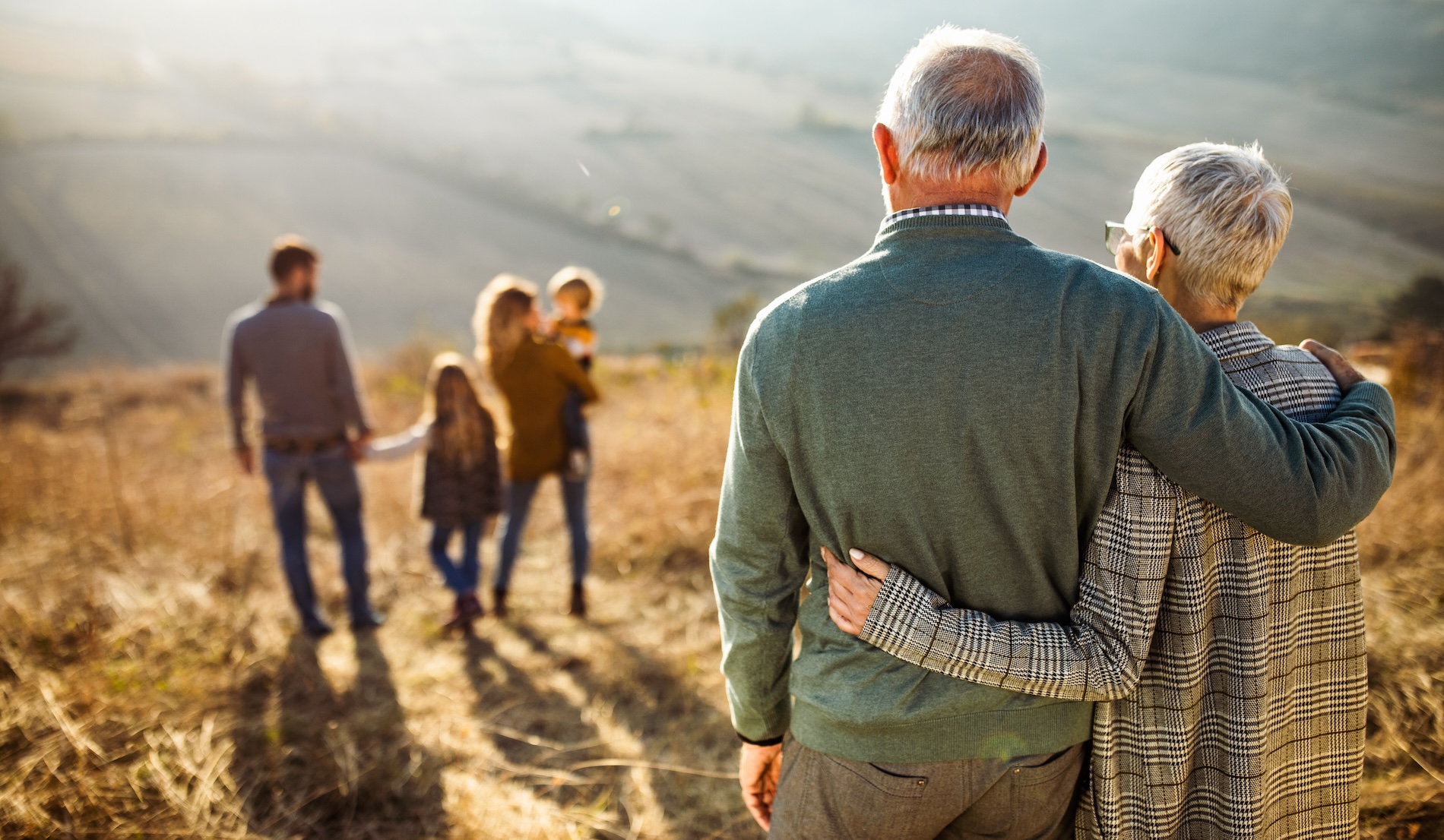 Vault Metal - Man and woman in their 70s overlooking their family walking peacefully through field at sunset.